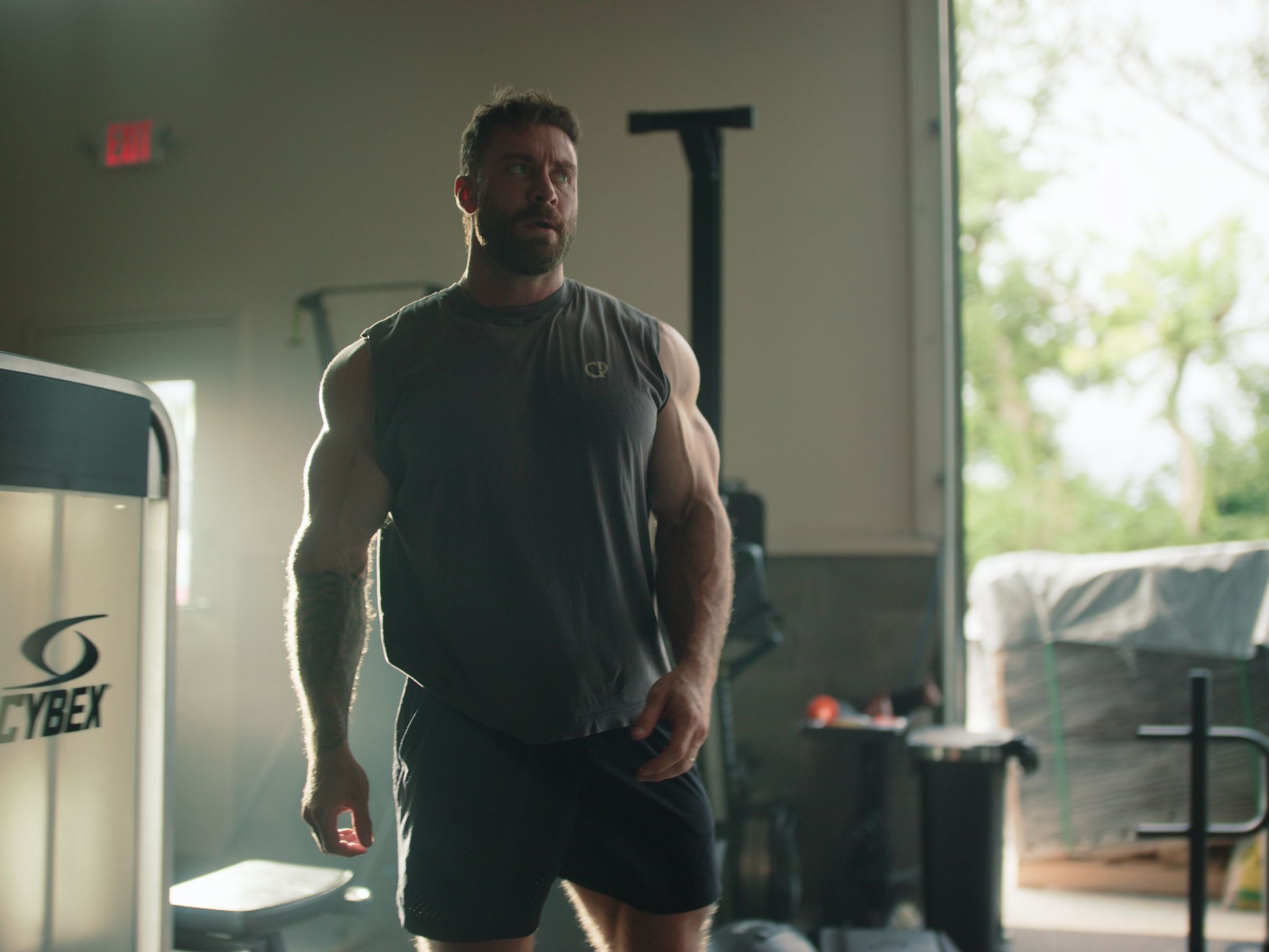 A fighter stands in the doorway of a gym, lit from behind