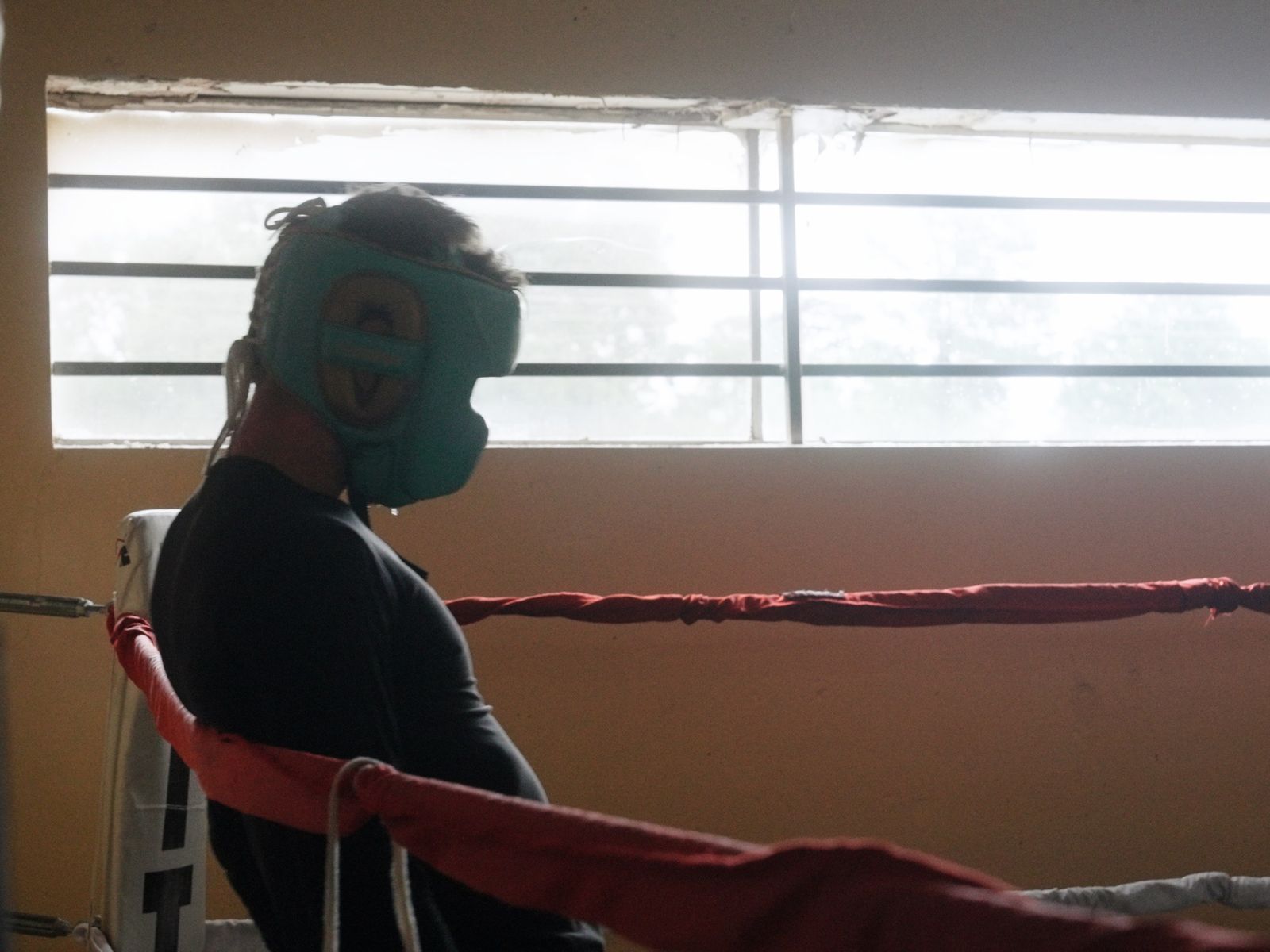 A fighter in headgear rests on the ropes