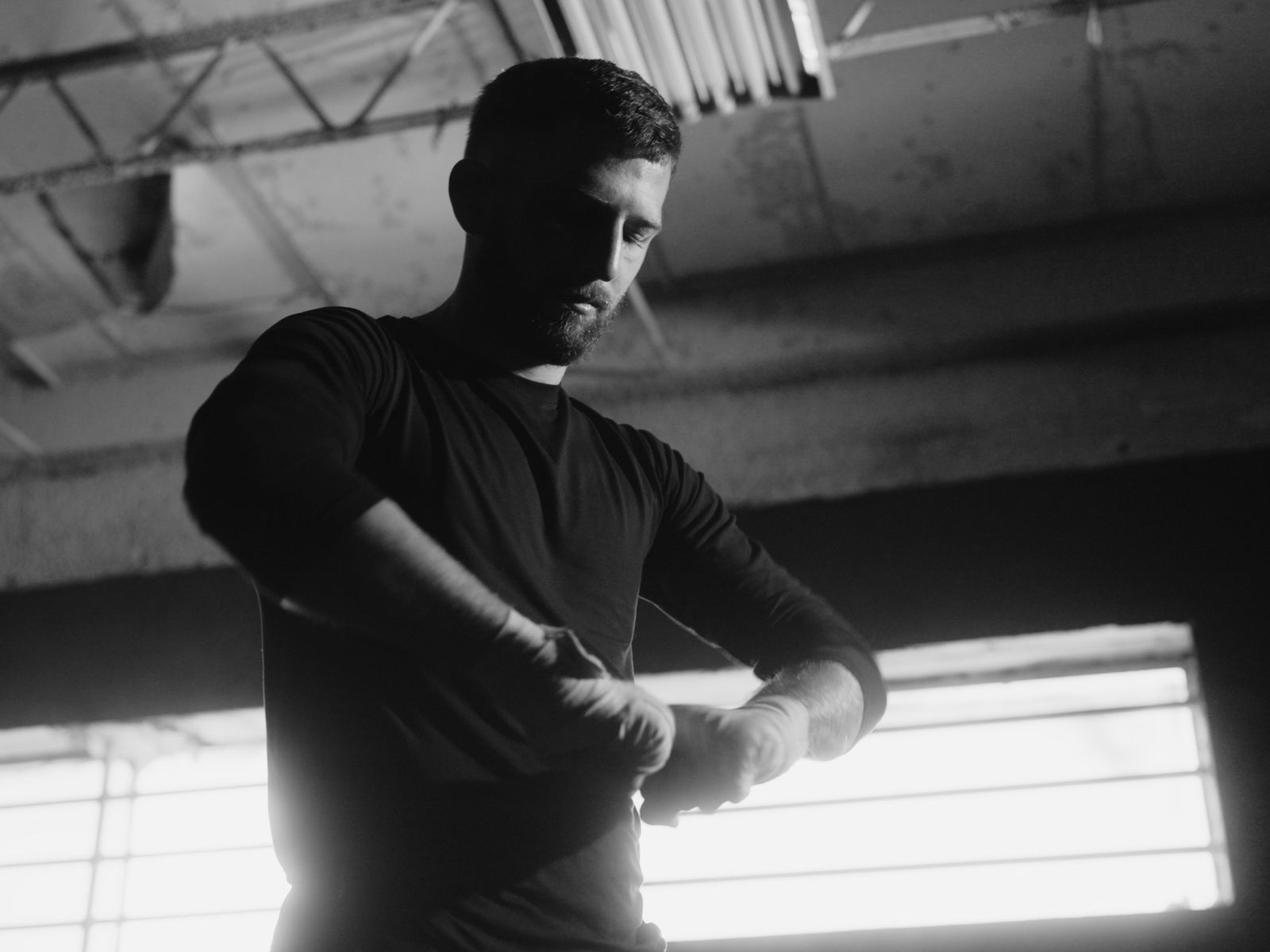 A fighter wraps his hands by the gym window